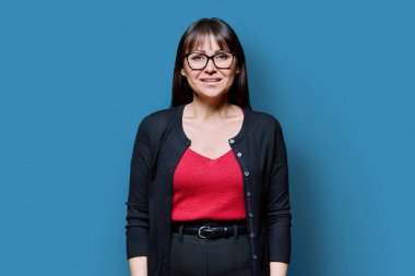 Mavi stüdyo geçmişinde gülümseyen orta yaşlı bir kadın. Kameraya bakan 40 'lı yaşlarda mutlu bir kadın. Yaşam tarzı, iş, güzellik, uzmanlık, sağlık, olgun insanlar konsepti