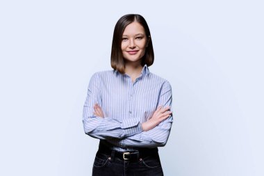 Beyaz stüdyo geçmişinde çapraz kollu, güler yüzlü genç bir iş kadını. Gömlekli mutlu bir kadın, kameraya bakan bir girişimci öğrenci. İş eğitimi alan insanlar