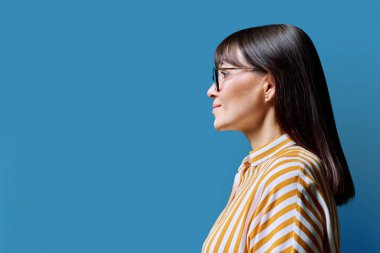 İleri bakan orta yaşlı bir kadının profil görüntüsü, mavi stüdyo arka planı, reklam metni için kopya alanı. Olgun iş, kendine güvenen başarılı kadın. Pazarlama satış hizmetleri, insanlar