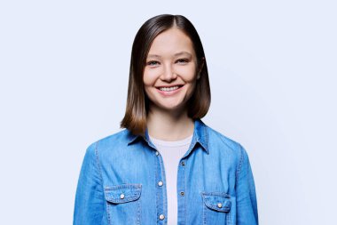 Beyaz stüdyo geçmişinde güzel, neşeli bir kadın. 20 'li yaşlarda, kot giyen ve kameraya bakan çekici bir kadın. Yaşam tarzı, moda güzellik tarzı, gençlik iş hizmetleri, eğitim