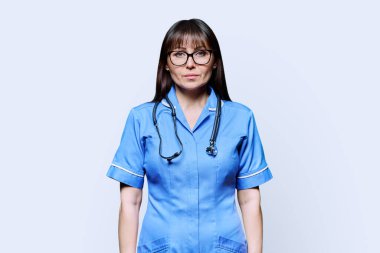Beyaz stüdyo arka planında steteskobu olan orta yaşlı kadın hemşire portresi. Tıbbi hizmetler, nhs, sağlık, mesleki yardım, tıbbi bakım kavramı