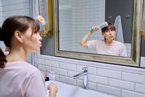 스프레이 빗이있는 여성은 거울을보고 스타일을하고 욕실에서 아름다움 화장품 액세서리 — 스톡 사진