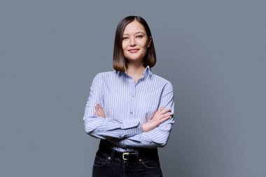 Gri stüdyo geçmişinde çapraz kollu, güler yüzlü genç bir iş kadını. Gömlekli mutlu bir kadın, kameraya bakan bir girişimci öğrenci. İş eğitimi alan insanlar