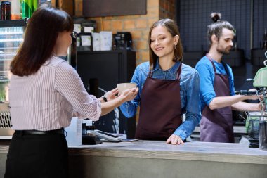 Kahve dükkanının kadın müşterisi bir fincan kahveyle restoran sahipleriyle konuşuyor. Bardaki işyeri, iş arkadaşları, yemek servisi ortakları, iş, girişimcilik, küçük işletme