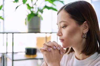 Heyecanlı üzgün üzgün, elleri katlanmış, yüzü profil yakından çekilmiş ciddi bir genç kadın. Duygular stres depresyonu zorluklar, akıl sağlığı, gençlik yaşam tarzı konsepti