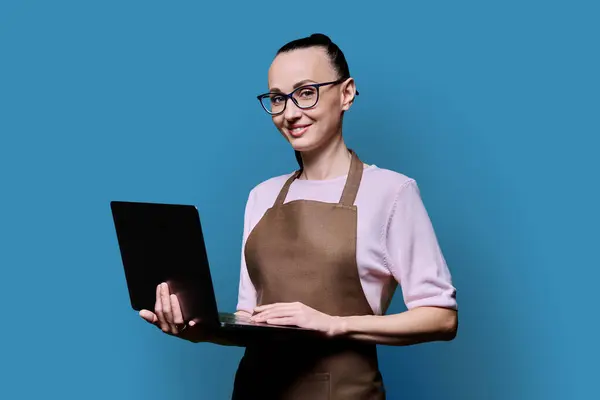 Portret Letniej Uśmiechniętej Kobiety Fartuchu Laptopem Patrzącej Kamerę Niebieskim Tle Obraz Stockowy