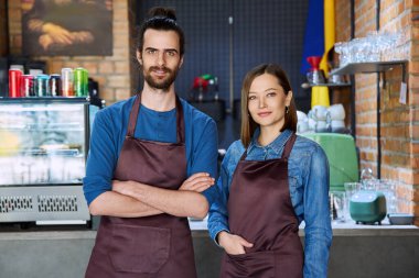Kendine güvenen başarılı iş arkadaşlarının küçük iş arkadaşları portresi restoran kafeteryasındaki iş yerinde kameraya bakan önlüklü genç bir kadın ortak. Ortaklık takım çalışması.