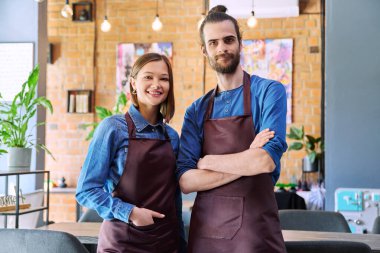 Kendine güvenen başarılı iş arkadaşlarının küçük iş arkadaşları portresi restoran kafeteryasındaki iş yerinde kameraya bakan önlüklü genç bir kadın ortak. Ortaklık takım çalışması.