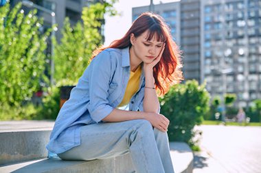 Üzgün, mutsuz, genç bir bayan merdivenlerde oturuyor. Kız üniversite öğrencisi, el ele tutuşarak oturuyor. Sorunlar, zorluklar, depresyon, gençlerin zihinsel sağlığı