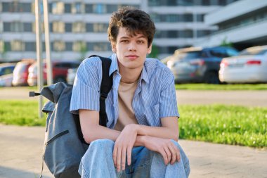 Portrait of confident smiling college student guy, young male with backpack looking at camera, urban outdoor. Education, lifestyle, 19,20 years age youth concept clipart