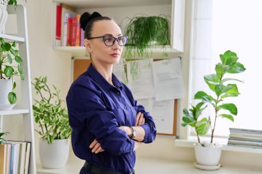 Kollarını kavuşturup pencereden dışarı bakan düşünceli, kendine güvenen bir kadın. Duygular, yaşam tarzı, sağlık, insan kavramı