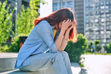 Üzgün, mutsuz, genç bir bayan merdivenlerde oturuyor. Kız üniversite öğrencisi, el ele tutuşarak oturuyor. Sorunlar, zorluklar, depresyon, gençlerin zihinsel sağlığı