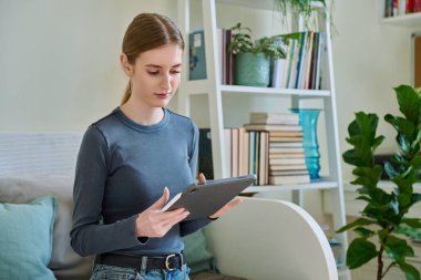 Dijital tabletli genç bir bayan. Stylus evde kanepede otururken resim çiziyor. Teknolojiler, eğlence, yaratıcılık, eğitim, serbest çalışma, yaşam tarzı, gençlik kavramı