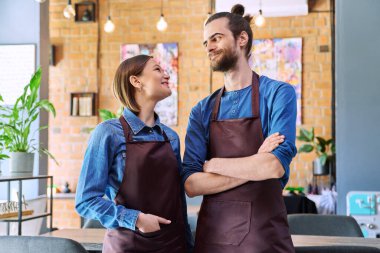 Küçük işletme ekibi, başarılı iş arkadaşları ortaklar önlüklü genç adam ve kadın restoran kafeteryasında konuşuyorlar. İşbirliği, ortaklık, takım çalışması, personel, iş