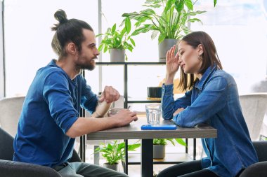 Genç çift kafede otururken ciddi bir konuşma yapıyor. İlişkiler zorluklar, sorunlar, olumsuz duygular, insan konsepti.