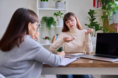 Terapi seansında psikoterapist psikologla konuşan üzgün genç kız. Gençliğin akıl sağlığı, zihinsel destek için sosyal hizmetler, psikolojik danışmanlık