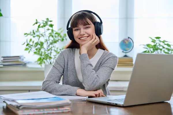 stock image Portrait of teenage college student wearing headphones, sitting at desk, smiling and looking at camera. Education, training, youth 18,19, 20 years old