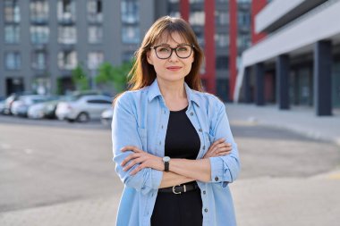 Şehir tarzında kameraya bakan orta yaşlı bir kadının portresi. 40 'lı yaşlar, yaşam tarzı, kariyer, kentsel yaşam konsepti