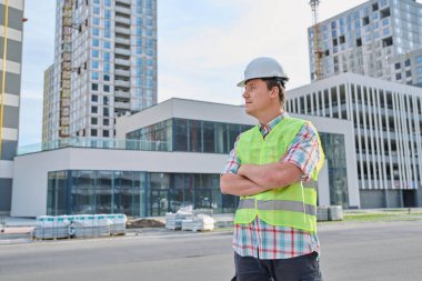 Genç kendinden emin erkek mühendis müteahhit endüstri işçisi inşaat sahasında ileriye, dışarı bakıyor. Endüstri teknik denetim, mühendislik hizmeti geliştirme çalışma kavramı