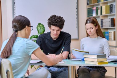Bir grup lise öğrencisi kütüphane sınıfında çalışıyor, sınıf arkadaşları gülüyor, konuşuyorlar, tartışıyorlar, takım çalışması projesi, sınavlara ve sınavlara hazırlanıyorlar. Eğitim gençlik iletişimi
