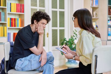 Ofis eğitim binasında genç bir erkek üniversite öğrencisiyle çalışan kadın psikolog. Gençliğin akıl sağlığı, sosyal hizmet, psikoloji, psikoterapi, davranış, destek tedavisi danışmanlığı