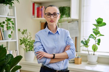 Gözlüklü, kolları çaprazlanmış, ev içi kameraya bakan 30 'lu yaşların zarif iş kadınının portresi. Yaşam tarzı, sağlık, kadın yaşam konsepti