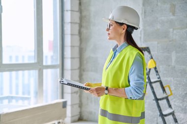 Güvenlik kasklı teknik uzman kadın inşaat işinde çalışıyor. Ciddi endüstriyel kadın mühendis müfettiş müfettişi belgeli mimar. İnşaat endüstrisi