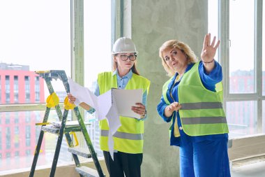 İnşaat alanında iş planlarını tartışan iki kadın sanayi işçisi. Endüstri, inşaat, inşaat, geliştirme, mimari, teknik üretim mesleklerinde kadınlar