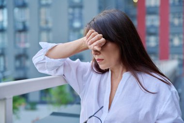 Stres, baş ağrısı, menopoz semptomları, sağlık sorunları, açık hava modern şehir geçmişi olan olgun bir kadın. Depresyon, stres, zorluklar, zihinsel sağlık konsepti
