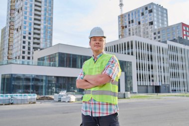 İnşaat alanında çalışan kendinden emin erkek mühendis müteahhit sanayi işçisi dışarıda kameraya bakıyor. Endüstri, teknik denetim, mühendislik hizmeti, geliştirme, iş kavramı