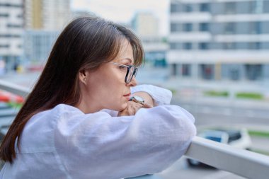 Üzgün, stresli, olgun bir kadın, açık hava portresi. Orta yaşlı ciddi bir kadın, şehir geçmişi var. Depresyon, stres, sorunlar, zorluklar, zihinsel sağlık kavramı