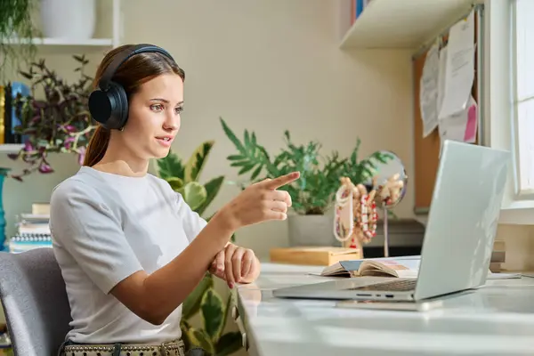 stock image Teenage girl college student in headphones having video conference chat online meeting lesson webinar on computer laptop screen, sitting at desk at home. E-learning, education, technology, knowledge