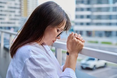 Dua ederken el ele tutuşan olgun, ciddi bir kadın. Yüzü kapalı, şehir dışı geçmişi var. Din, umut, yaşam tarzı, olgunluk, zihinsel yaşam, insan kavramı