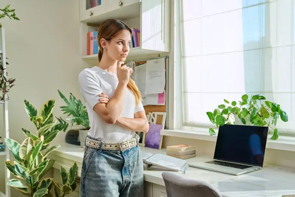 stock image Portrait serious thoughtful teenage girl looking out the window, at home. Youth, lifestyle, 17, 18, 19 years old age concept