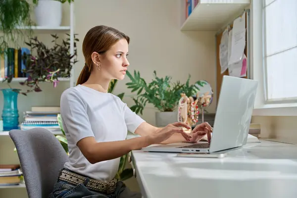 stock image Female teenager college student studying at home sitting at desk with laptop computer in room. Education, lifestyle, teenage youth concept