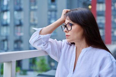 Sad upset stressed mature woman, outdoor portrait. Middle aged serious female, city urban background. Depression, stress, problems, difficulties, mental health concept clipart