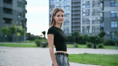 Güzel gülümseyen genç bir kadın kameraya, açık hava fotoğrafına, şehir arka planına bakıyor. Kızıl uzun saçlı genç kız, gülümse beyaz dişler, mükemmel cilt