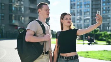 Arkadaş gençler mutlu mutlu gülümseyen üniversite öğrencileri erkek ve kız birlikte fotoğraf çekiyorlar akıllı telefon, açık hava, şehir arka planı. Gençlik 17-18 yaş eğitim yaşam tarzı başarı arkadaşlığı