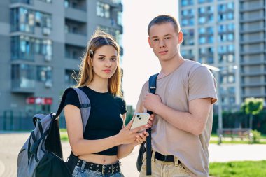 Genç öğrencilerin portresi, erkek ve kız, birlikte açık havada, şehir arka planına bakarak. Gençlik, 17, 18, 19 yaşında, yaşam tarzı, insanlar konsepti