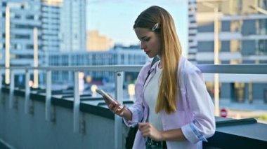 Akıllı telefon kullanan genç bir kadın, modern şehir geçmişi. Ergen öğrenci gezmek için mobil uygulama uygulamaları kullanarak mesajlaşıyor. Teknoloji İnternet Eğitim Gençlik Usulü