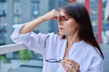 Stres, baş ağrısı, menopoz semptomları, sağlık sorunları, açık hava modern şehir geçmişi olan olgun bir kadın. Depresyon, stres, zorluklar, zihinsel sağlık konsepti