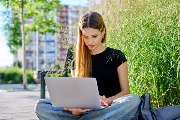 stock image Young attractive female college student using computer typing on laptop outdoor, modern urban background. Education, technology, training, 17, 18 years age youth concept