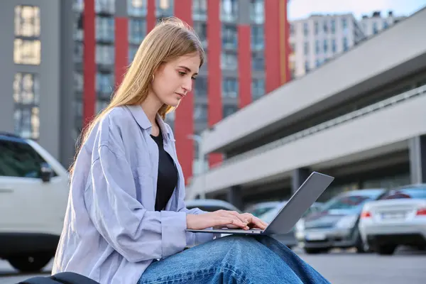 stock image Young attractive serious female college student using laptop computer outdoor, modern urban background. Education, technology, training, 17, 18 years age youth concept