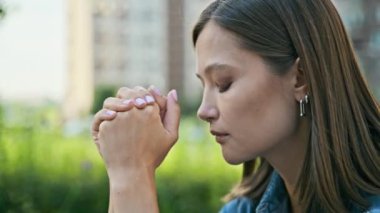 Endişeli, sinirli, genç bir kadın dışarıda yüzünü kapatıyor. Gergin, stresli, elleri dua meditasyonunda katlanmış, profil görünümlü kadın. Akıl sağlığı, olumsuz duygular, yaşam tarzı