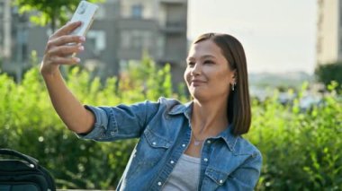 Genç ve güzel bir kadın akıllı telefondan görüntülü konuşma yapıyor. Şehir dışında. Çevrimiçi toplantı, video iletişimi, teknoloji, yaşam tarzı, gençlik kavramı