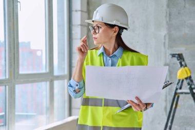 Güvenlik kasklı teknik uzman kadın inşaat işinde çalışıyor. Ciddi endüstriyel kadın mühendis müfettiş müfettişi belgeli mimar. İnşaat endüstrisi