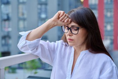 Stres, baş ağrısı, menopoz semptomları, sağlık sorunları, açık hava modern şehir geçmişi olan olgun bir kadın. Depresyon, stres, zorluklar, zihinsel sağlık konsepti