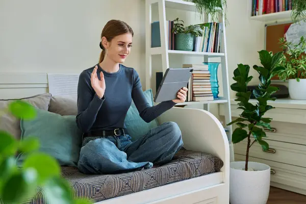 Genç kız öğrenci evde oturmuş dijital tabletin web kamerasıyla konuşuyor. 16,17,18 yaşında kız uzaktan eğitim, video konferans çağrısı, e-öğrenim teknolojisi eğitimi