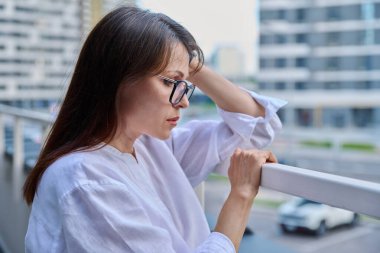 Üzgün, stresli, olgun bir kadın, açık hava portresi. Orta yaşlı ciddi bir kadın, şehir geçmişi var. Depresyon, stres, sorunlar, zorluklar, zihinsel sağlık kavramı