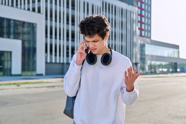 Genç, yakışıklı, ciddi bir adam cep telefonuyla konuşuyor, modern şehir geçmişi, şehir tarzı. Gençlik, yaşam tarzı, iletişim duyguları, şehir konseptinde yaşam